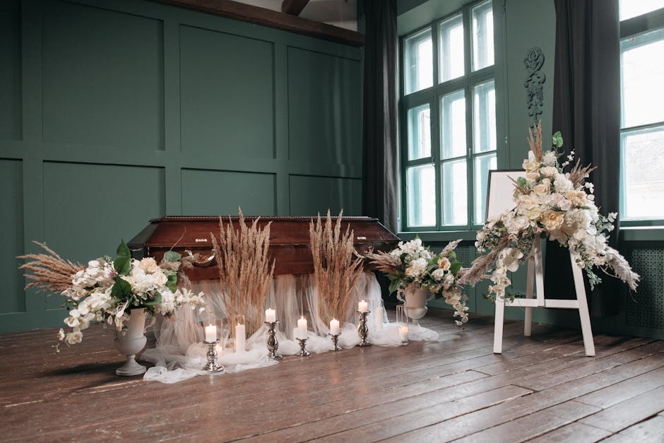 A floral arrangement featuring white roses, lilies, and assorted white blooms, accented with beige pampas grass, set in white vases on either side of a vintage wooden piano. The display is decorated w
